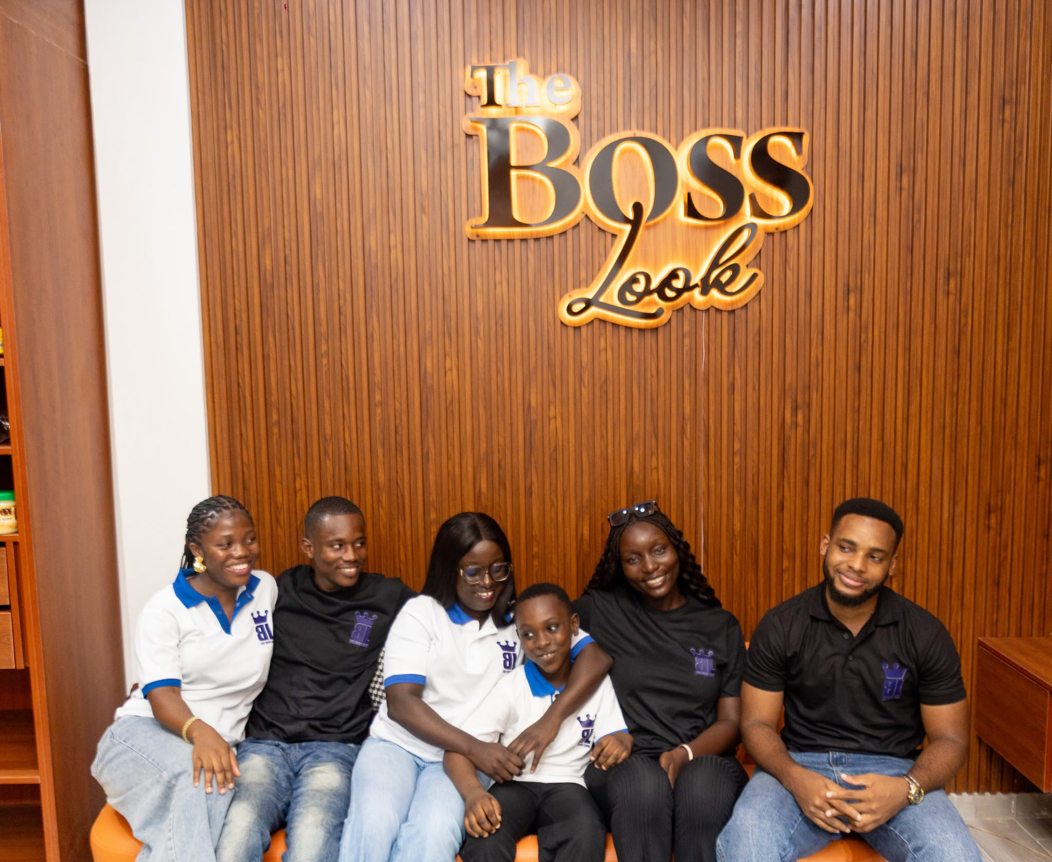 The Boss Look team gathered together under the wall sign